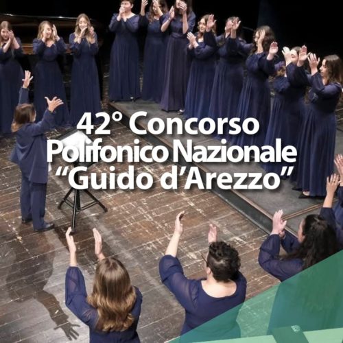 Un coro di donne in abito blu canta sul palco, guidato da un direttore d'orchestra. Il testo recita: 42° Concorso Polifonico Nazionale Guido dArezzo. L'evento è organizzato dalla Fondazione Guido dArezzo.